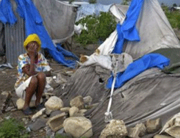 A Haitian woman by her destroyed tent