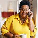 Woman on the phone holding a cup of coffee.