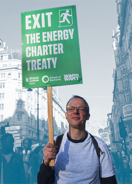 A demonstrator holds a sign that reads 'Exit the Energy Charter Treaty' 