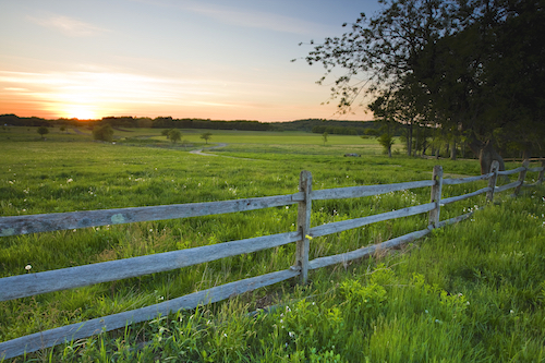 sweeping farm fields with split rail fence in the foreground