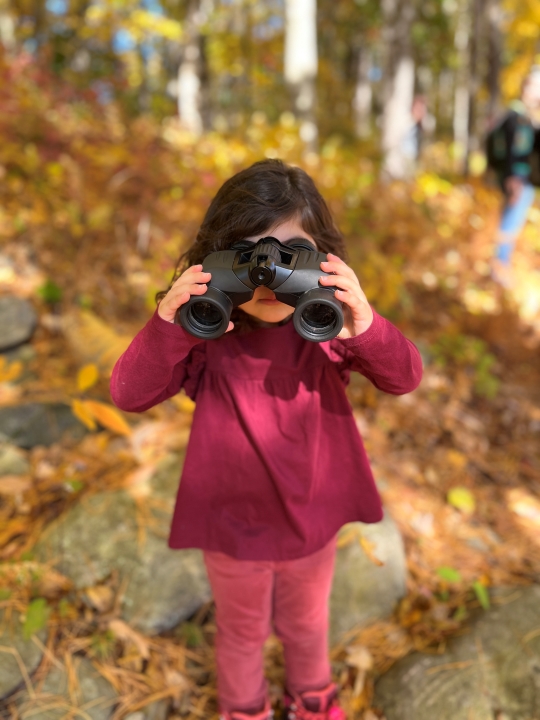 Girl looks through binoculars at All About Beavers