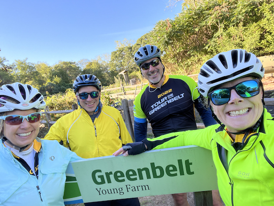 four cyclists in bright jerseys in front of Greenbelt sign