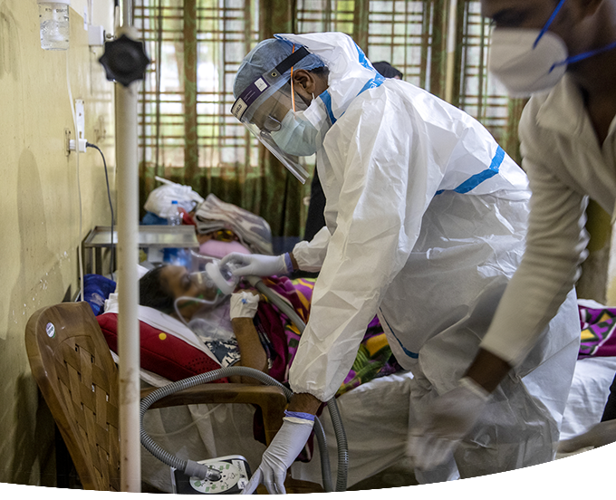 Doctor in PPE holding oxygen mask for patient.